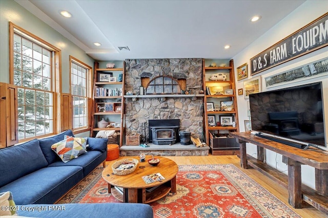 living area featuring a wood stove, visible vents, wood finished floors, and recessed lighting