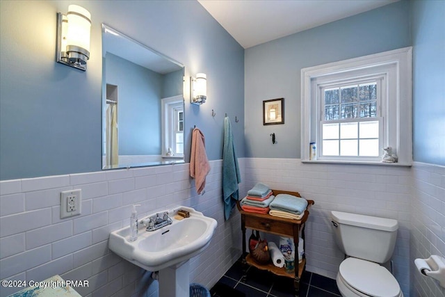 full bathroom featuring a wainscoted wall, a sink, toilet, and tile patterned floors