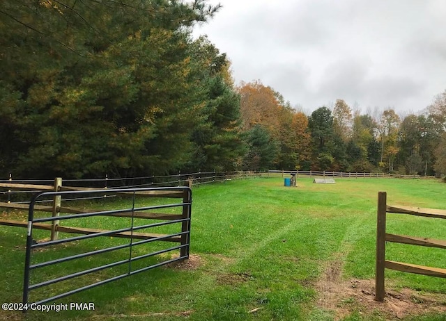 view of gate featuring a yard, a forest view, and fence