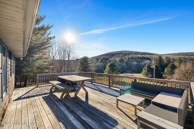 deck featuring an outdoor living space and a wooded view