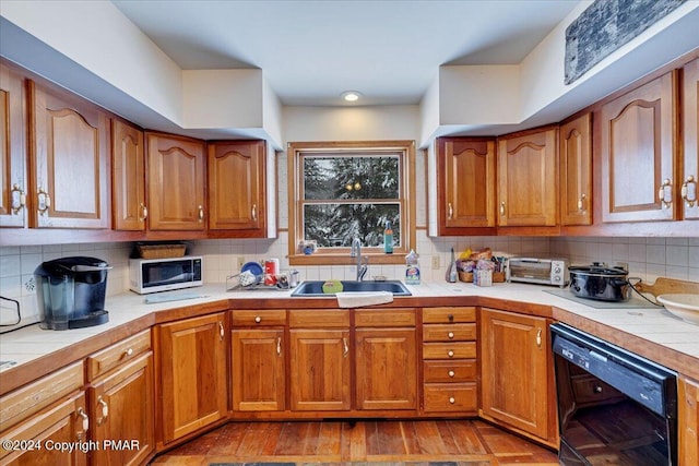 kitchen featuring tile counters, black dishwasher, a sink, and white microwave