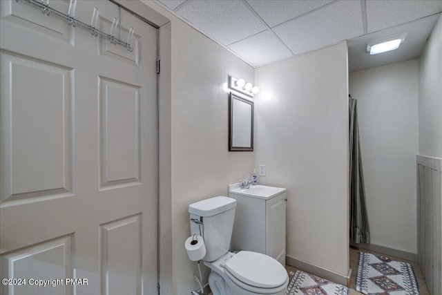 bathroom featuring curtained shower, a drop ceiling, toilet, vanity, and baseboards