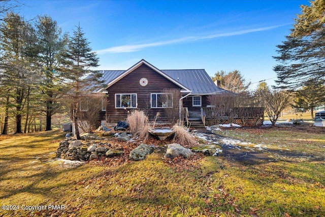 view of front of property featuring a standing seam roof, a front yard, metal roof, and a wooden deck