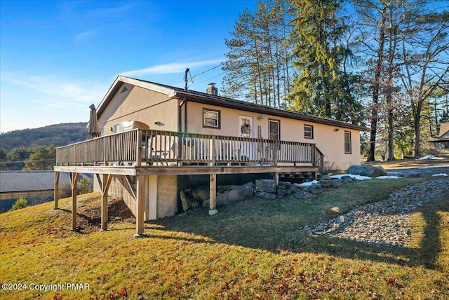 back of property featuring a lawn, a wooden deck, and fence