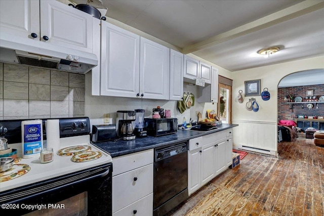 kitchen with a wainscoted wall, white cabinetry, a sink, under cabinet range hood, and black appliances