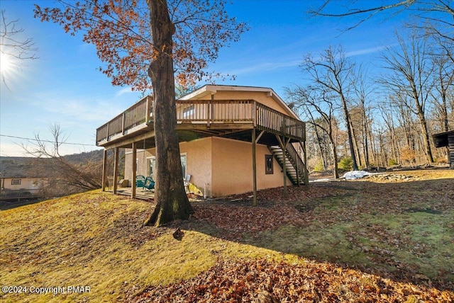 rear view of house featuring stairs, a deck, and stucco siding