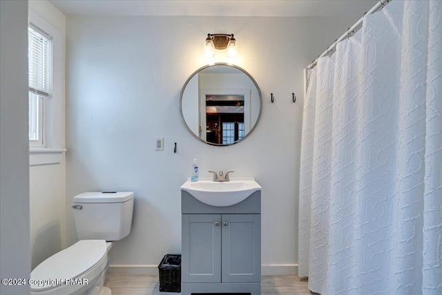 full bath featuring wood finished floors, vanity, toilet, and baseboards