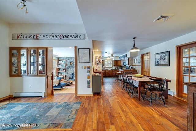 dining room featuring a baseboard radiator, visible vents, baseboards, a ceiling fan, and wood-type flooring