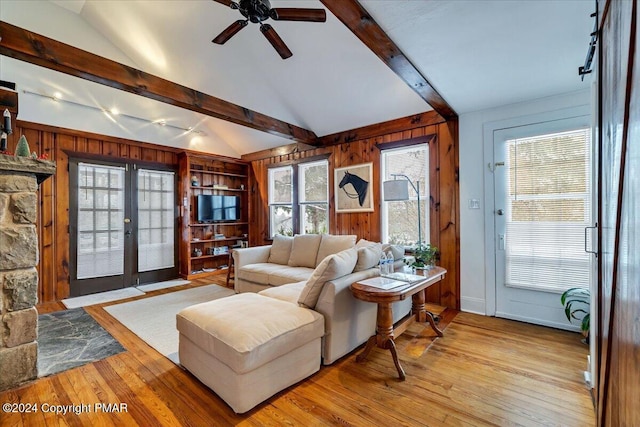 living room with wooden walls, french doors, lofted ceiling with beams, and hardwood / wood-style flooring