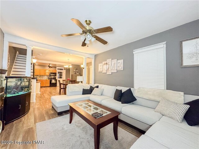 living room featuring ceiling fan with notable chandelier, decorative columns, and hardwood / wood-style floors