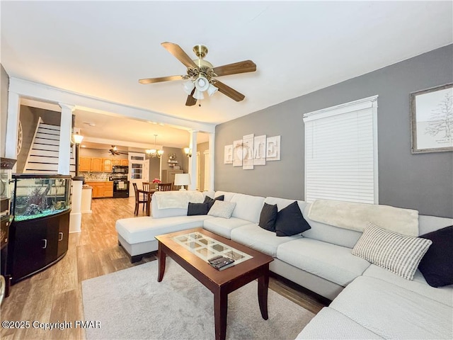 living room with ceiling fan with notable chandelier, decorative columns, and hardwood / wood-style floors