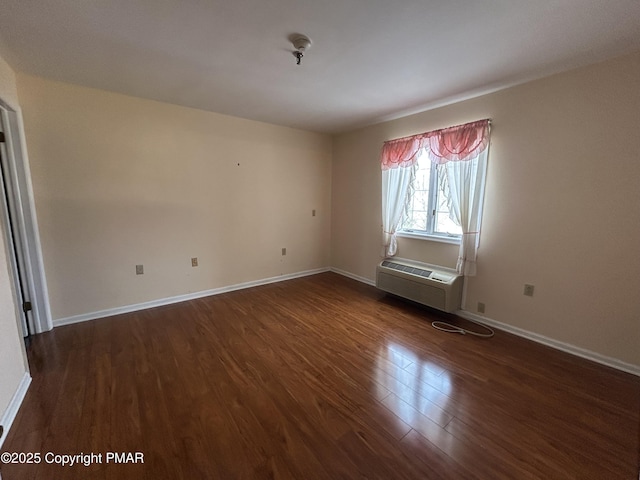 empty room with dark wood finished floors, an AC wall unit, and baseboards