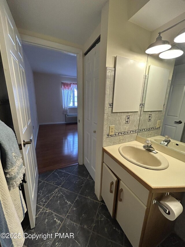 bathroom with vanity, marble finish floor, and backsplash