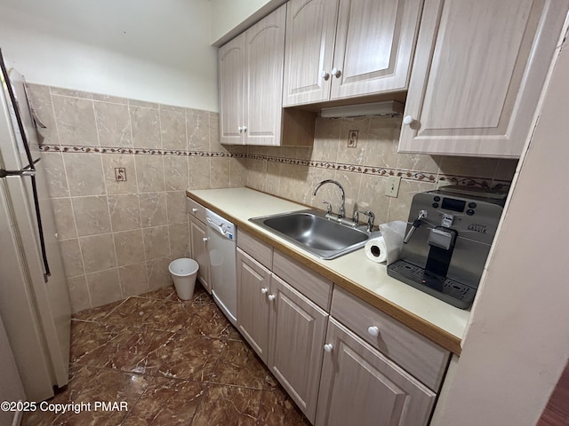 kitchen featuring freestanding refrigerator, dishwashing machine, light countertops, and a sink