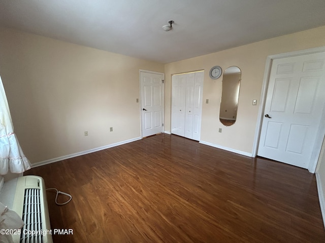 spare room with heating unit, wood finished floors, and baseboards