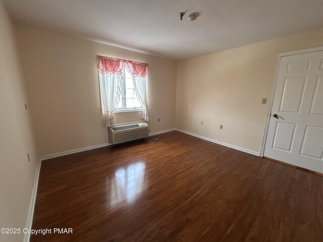 spare room featuring dark wood-type flooring and baseboards