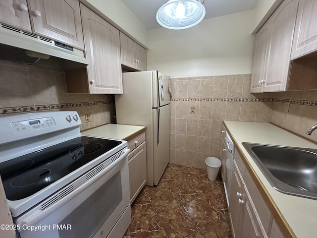 kitchen with white appliances, a sink, light countertops, under cabinet range hood, and tile walls