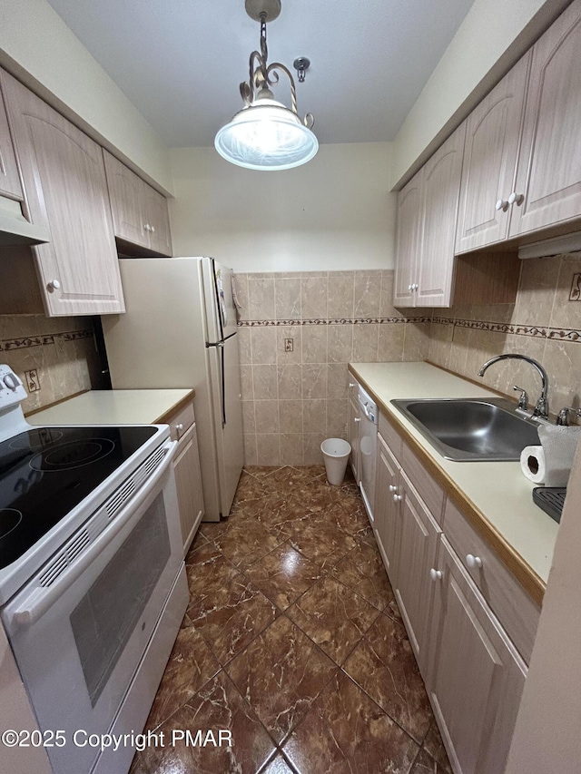 kitchen with light countertops, electric stove, hanging light fixtures, tile walls, and a sink