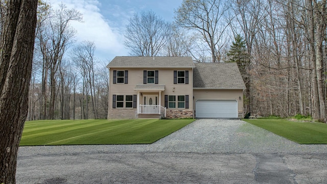 colonial house featuring roof with shingles, an attached garage, gravel driveway, and a front yard