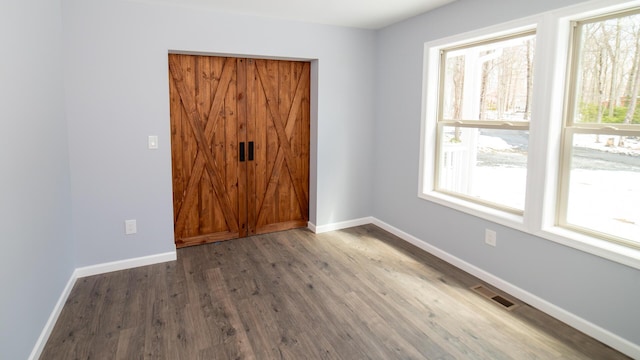 unfurnished bedroom with baseboards, wood finished floors, and visible vents