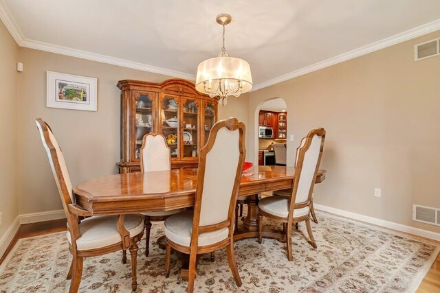 1376 Buck Ridge Dr, Stroudsburg, PA 18360 - dining room with a chandelier, arched walkways, baseboards, ornamental molding, and light wood-style flooring