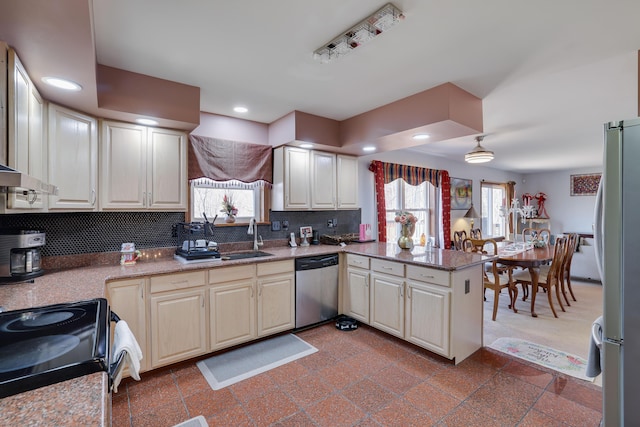 kitchen featuring a peninsula, recessed lighting, a sink, decorative backsplash, and stainless steel appliances