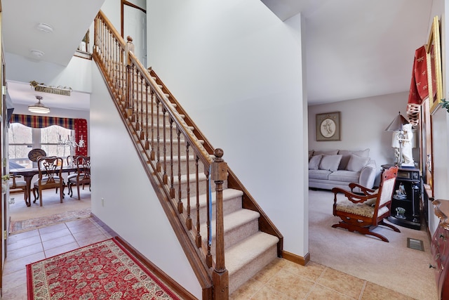 staircase with tile patterned floors, visible vents, baseboards, and carpet