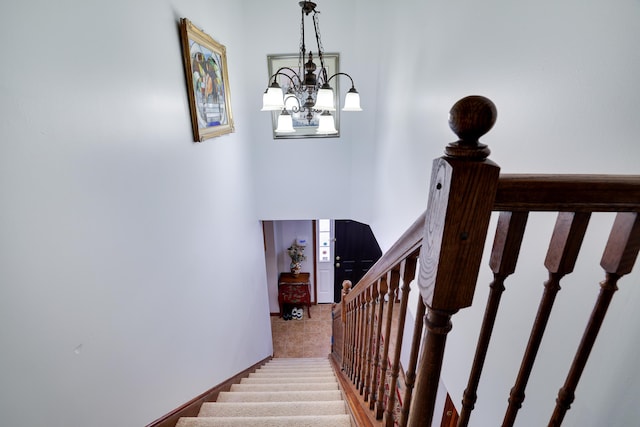 stairway with baseboards, carpet, and an inviting chandelier