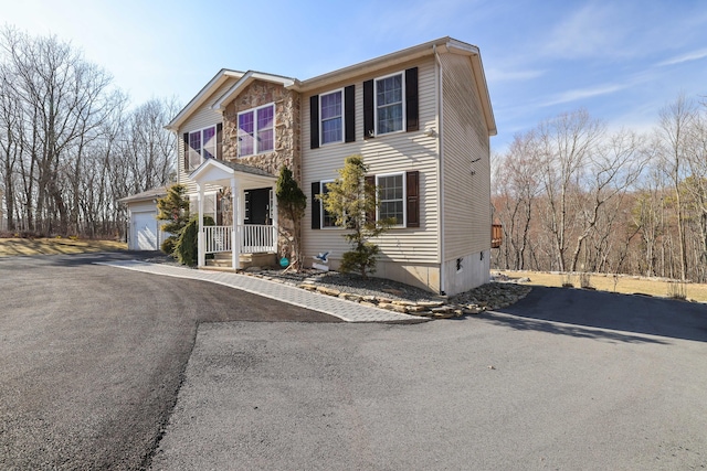 view of front of house with an attached garage, stone siding, and driveway