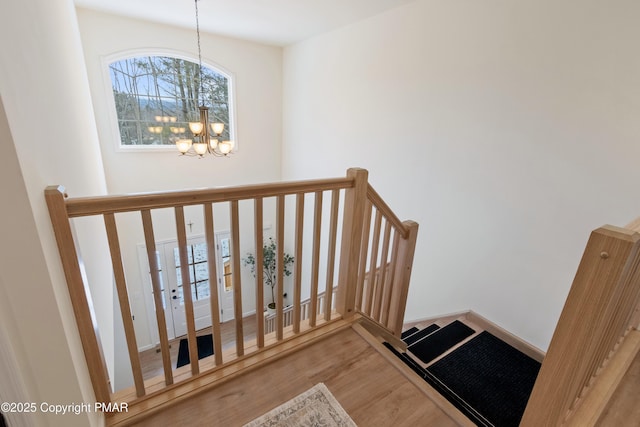 stairway featuring wood-type flooring and a chandelier