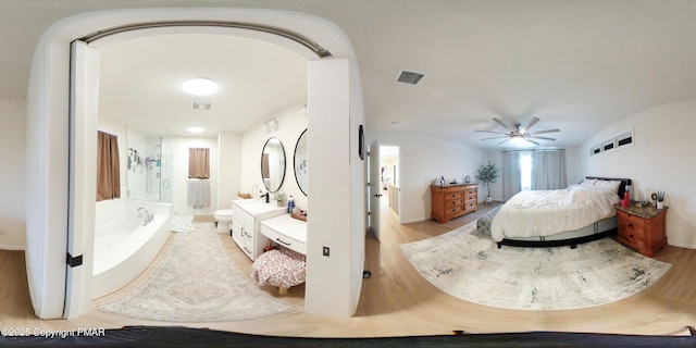 bedroom featuring ceiling fan, ensuite bathroom, light hardwood / wood-style floors, and lofted ceiling