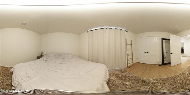 bedroom featuring hardwood / wood-style flooring, lofted ceiling, and a closet