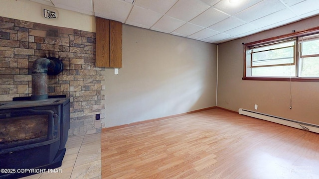 619 Rimrock Rd, Bartonsville, PA 18321 - unfurnished living room featuring light wood-style floors, a paneled ceiling, baseboard heating, and a wood stove