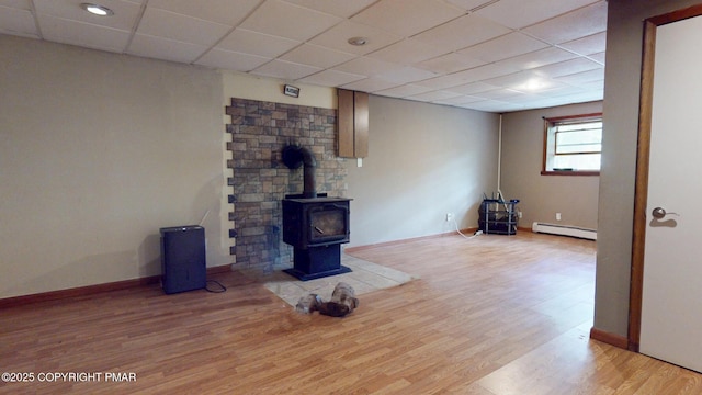 619 Rimrock Rd, Bartonsville, PA 18321 - unfurnished living room featuring a baseboard radiator, wood finished floors, a wood stove, and a paneled ceiling