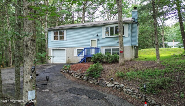 619 Rimrock Rd, Bartonsville, PA 18321 - view of front of home featuring a chimney, a garage, driveway, and a metal roof