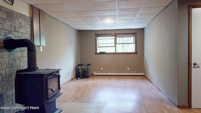 619 Rimrock Rd, Bartonsville, PA 18321 - living area featuring a baseboard heating unit, a wood stove, a paneled ceiling, and light wood-style floors