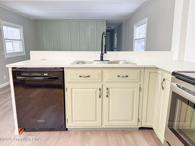 kitchen featuring black dishwasher, a healthy amount of sunlight, a sink, and light wood finished floors