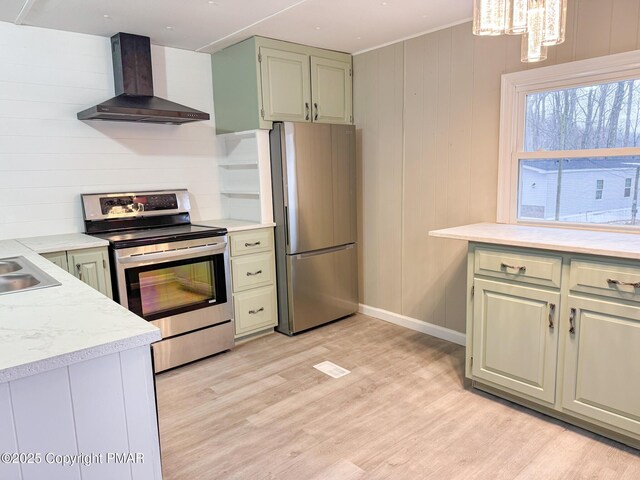 kitchen featuring wall chimney exhaust hood, sink, light wood-type flooring, wooden walls, and stainless steel appliances