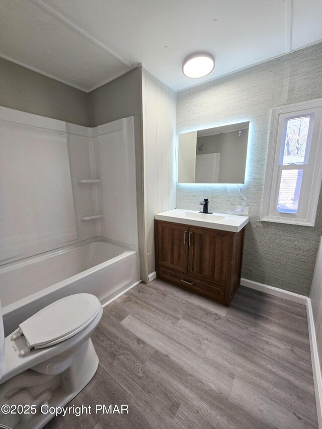 full bathroom with shower / bath combination, baseboards, toilet, wood finished floors, and vanity