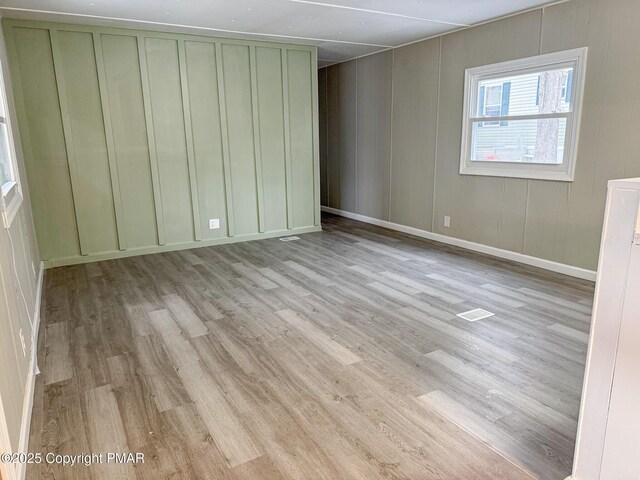 unfurnished bedroom featuring baseboards, a decorative wall, and wood finished floors