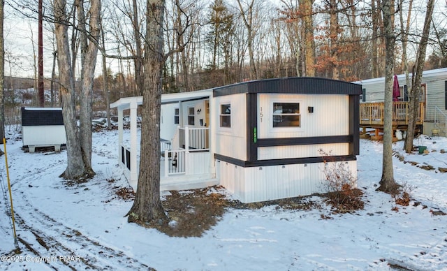 snow covered property featuring a storage shed and an outbuilding