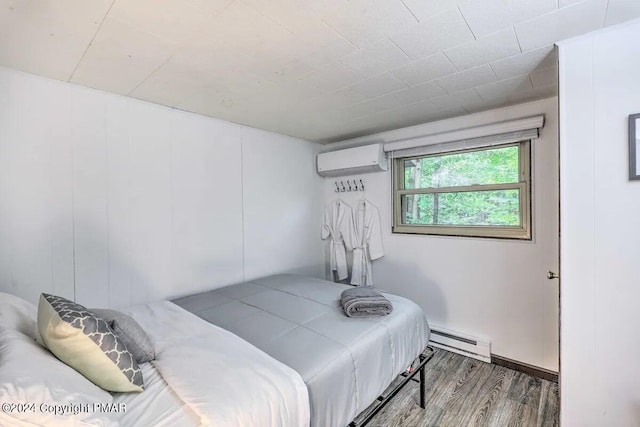 bedroom featuring a baseboard heating unit, a wall unit AC, and wood finished floors