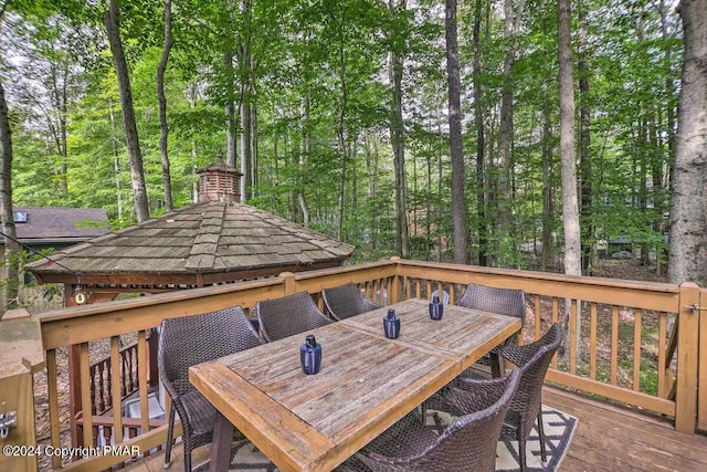 wooden deck featuring outdoor dining area and a gazebo