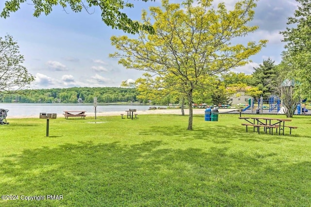 view of property's community with a water view, playground community, and a yard