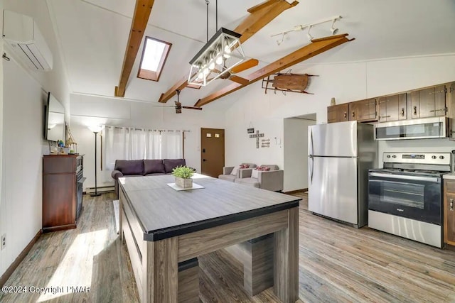 kitchen with light wood finished floors, lofted ceiling with skylight, appliances with stainless steel finishes, a wall mounted air conditioner, and baseboard heating