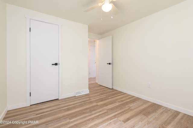 unfurnished bedroom featuring ceiling fan, light wood finished floors, visible vents, and baseboards