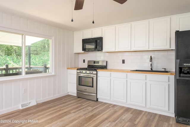 kitchen featuring visible vents, wooden counters, white cabinetry, a sink, and black appliances