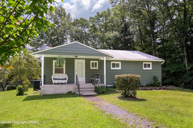 view of front of house featuring covered porch, central AC unit, and a front yard