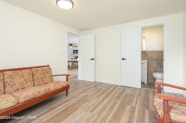 sitting room featuring light wood-type flooring, tile walls, and wainscoting