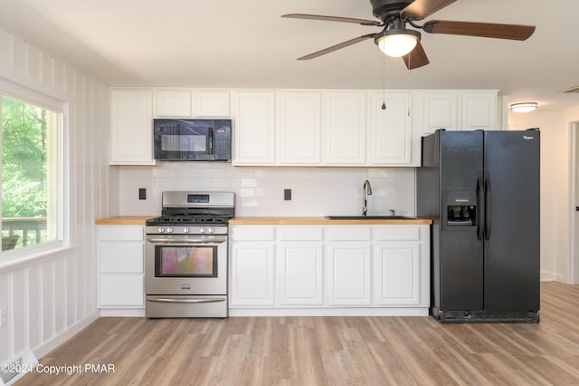 kitchen with light wood-type flooring, white cabinetry, a sink, and black appliances